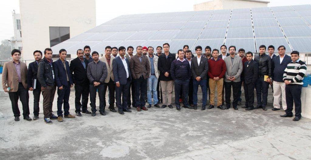 The CELRON Solar team together in front of a rooftop solar array